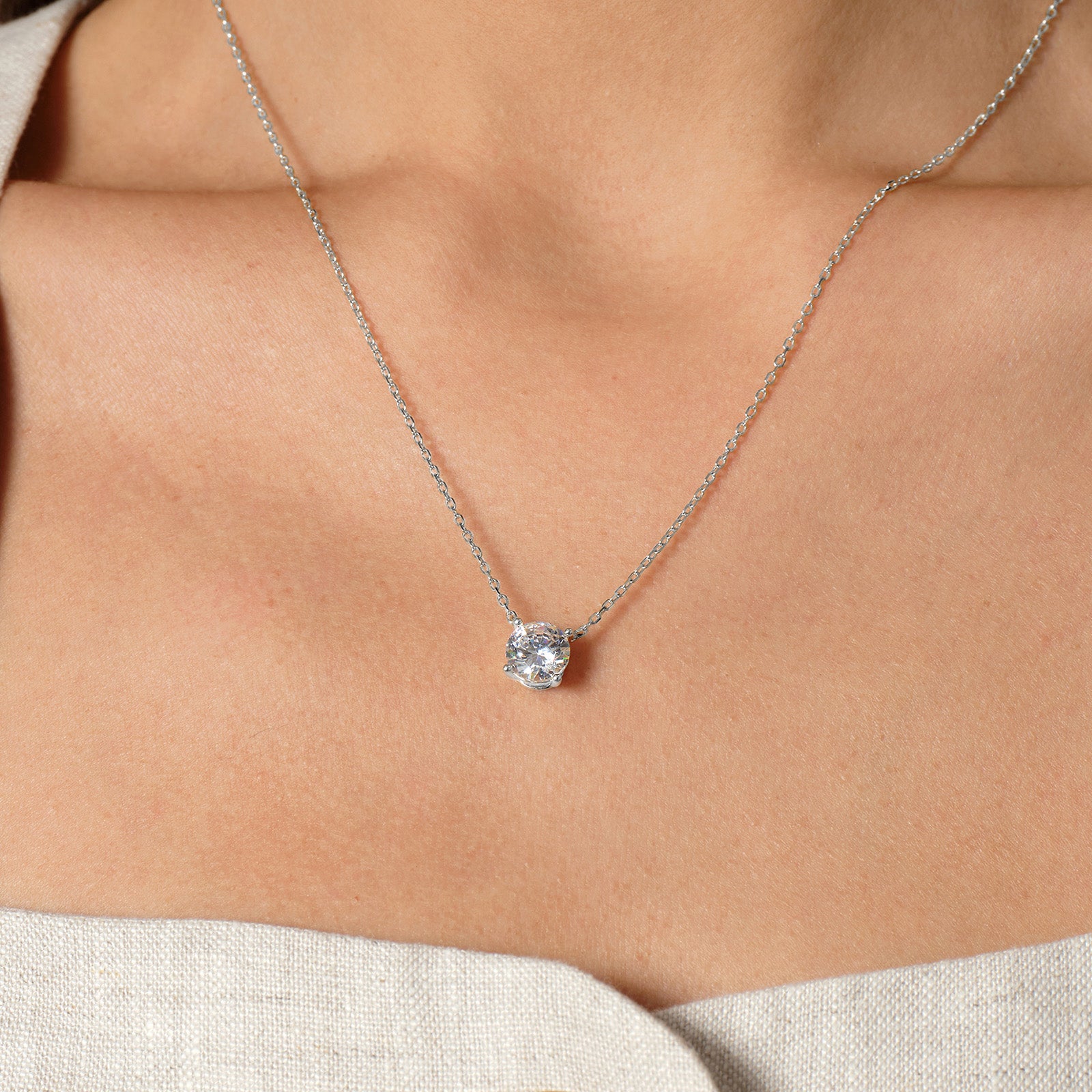 Model wearing round cubic zirconia solitaire pendant necklace in white gold color