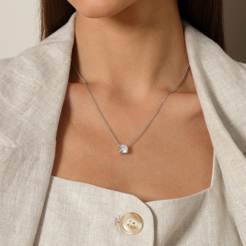 Model wearing round cubic zirconia solitaire pendant necklace in white gold color, close view