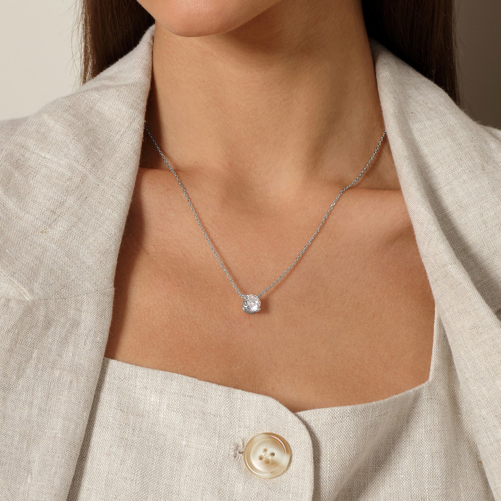 Model wearing round cubic zirconia solitaire pendant necklace in white gold color, close view