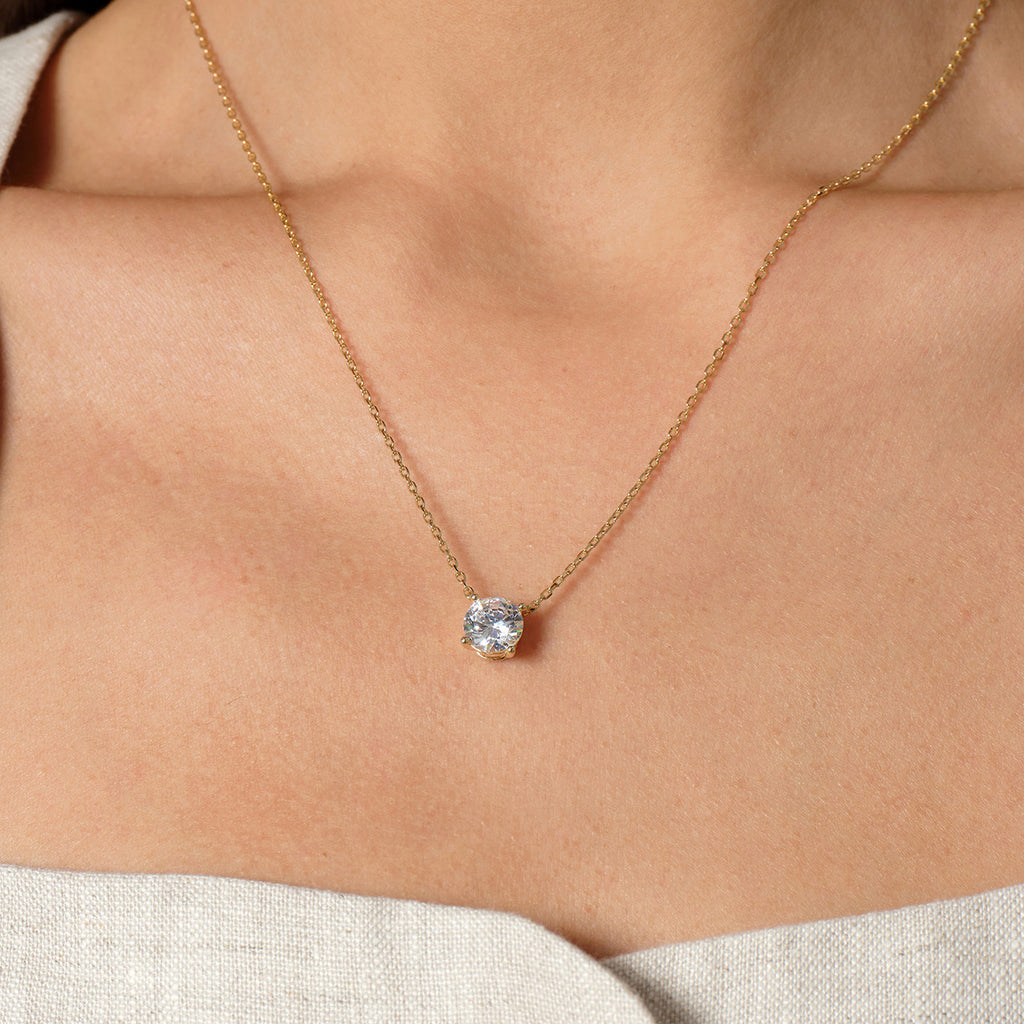 Model wearing round cubic zirconia solitaire pendant necklace in yellow gold color