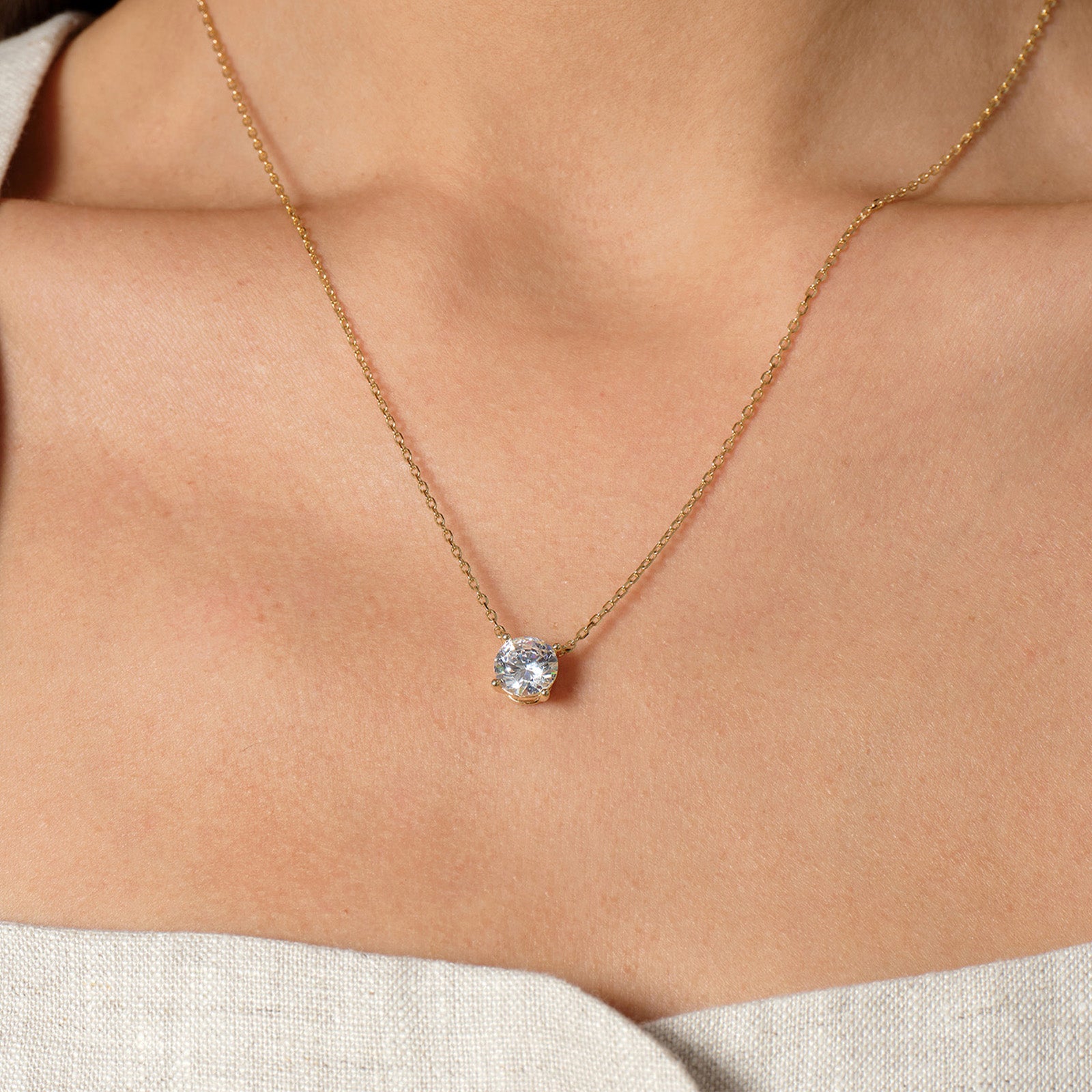 Model wearing round cubic zirconia solitaire pendant necklace in yellow gold color
