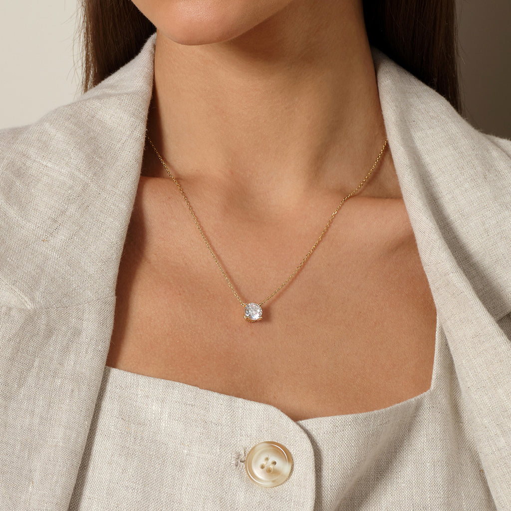 Model wearing round cubic zirconia solitaire pendant necklace in yellow gold color, close view