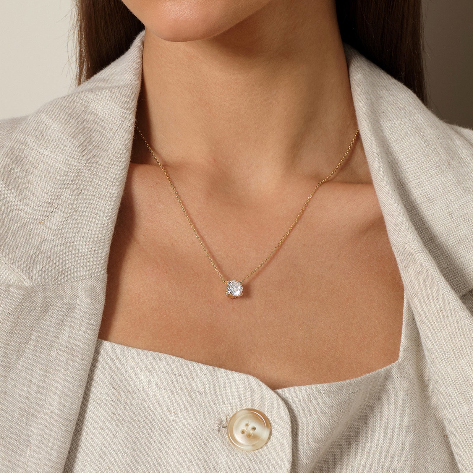 Model wearing round cubic zirconia solitaire pendant necklace in yellow gold color, close view