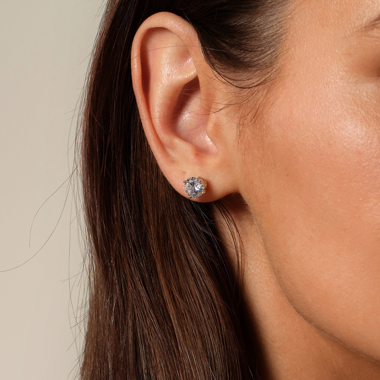 Close-up of model wearing round cubic zirconia stud earrings in gold color