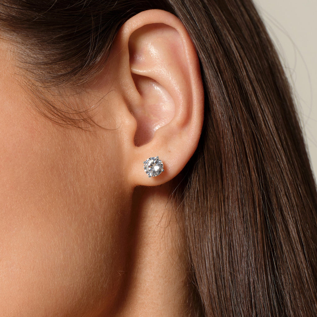 Model wearing round cubic zirconia stud earrings in silver color